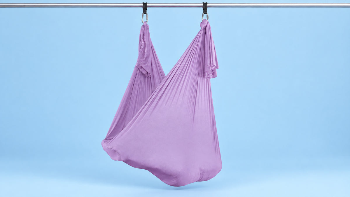 Flieder Aerial Yoga Tuch an zwei Punkten als Hängematte aufgehängt vor blauem Hintergrund