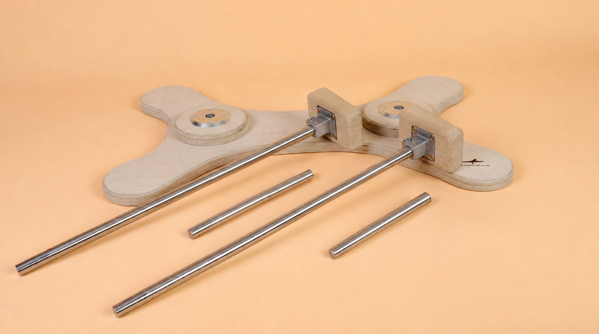 Modulares Handstand-Set mit zwei langen und zwei kurzen Metallstangen, zwei Holzgriffen und einer knochenförmigen Grundplatte auf beigem Untergrund