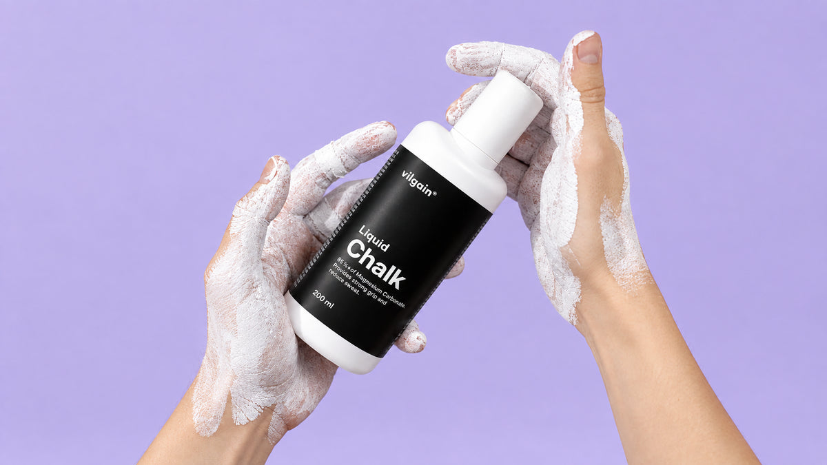 Hände mit weißem Flüssigkreide-Rückstand halten eine weiße Flasche mit schwarzem Etikett und der Aufschrift 'Liquid Chalk'